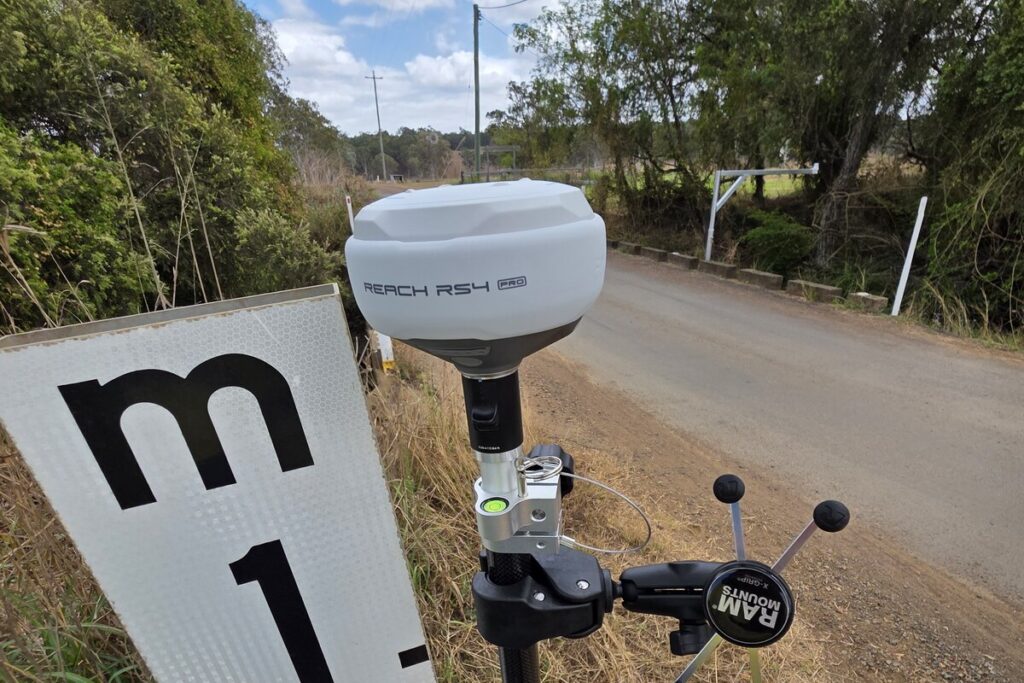 RTK GNSS rover surveying a low-cost flood gauge board